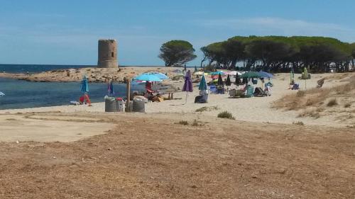 a group of people on a beach with umbrellas at Casa a pochi passi dal mare in La Caletta