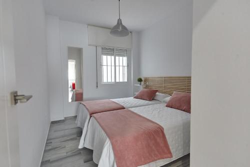 a white bedroom with a large bed with red pillows at APTARTAMENTO DOÑANA RECIEN REFORMADO Parking gratis in Sanlúcar de Barrameda
