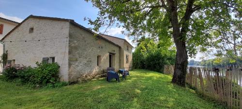 a building with a tree and a bench in the yard at L'Annexe Mauvilla in Civrac-de-Dordogne