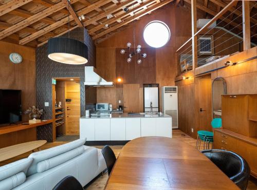 a living room with a table and a kitchen at SUMITSUGU HOUSE Atelier in Kumamoto