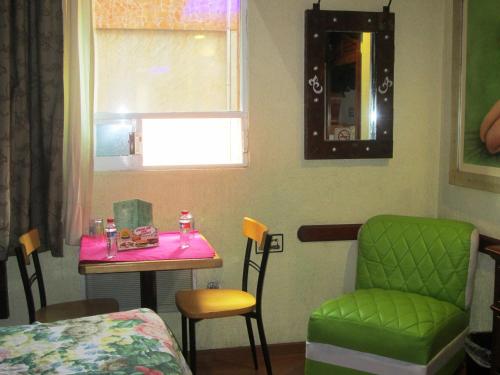 a room with a table and a green chair at Hotel Real Azteca in Mexico City
