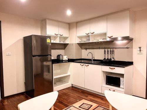 a kitchen with white cabinets and a stainless steel refrigerator at The Title Rawai: Beachfront condotel in Rawai Beach
