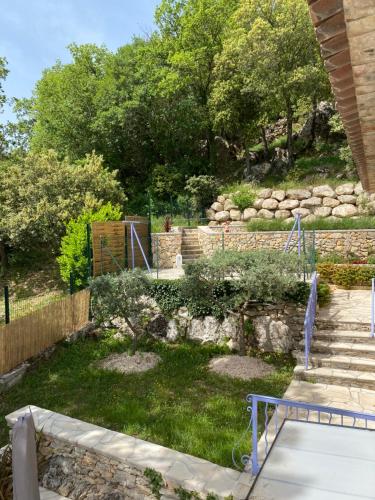 a garden with a stone retaining wall and stairs at Le Refuge in Montmeyan