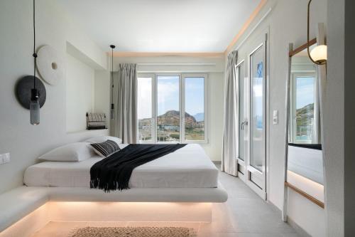 a white bedroom with a bed and a large window at Arkasa Palace in Arkasa