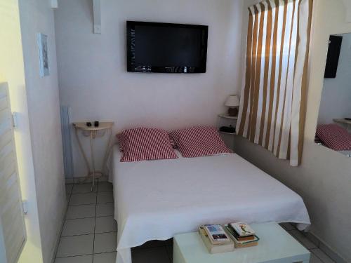 a small room with a bed and a tv on the wall at Bungalow Soleil in Sainte-Anne