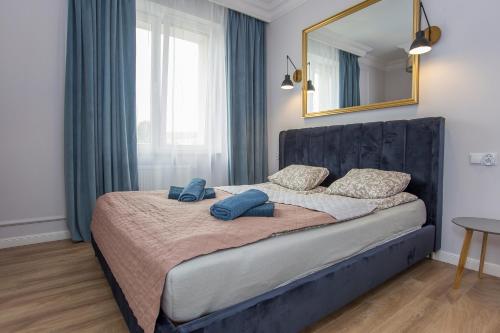 a bedroom with a bed with a mirror and blue pillows at Urban Jungle klimatyczny apartament w centrum in Białystok
