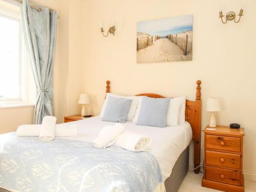 a bedroom with a bed with white and blue pillows at Ocean Watch 5 in Weymouth