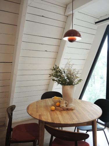 a wooden table with a vase of flowers on it at Domki MODERN Jezioro Nyskie in Nysa