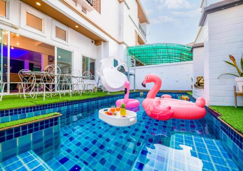 a swimming pool with two inflatable flamingos in the water at Room@Gallery Pool Villa in Pattaya South