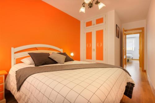 a bedroom with orange walls and a large bed at Apartamentos IRENE en el Pirineo Aragonés in Sabiñánigo