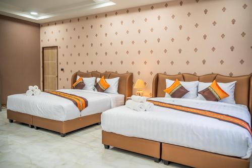 two beds in a hotel room with white and orange pillows at Siri Nakornpink Chiang Mai Hotel SHA Plus in Chiang Mai
