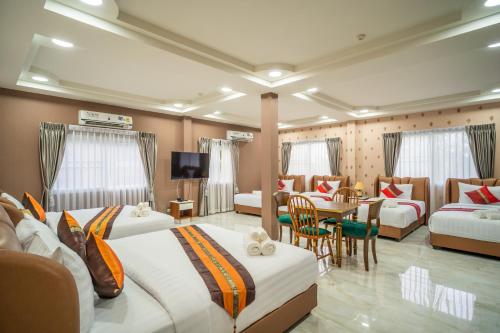 a hotel room with two beds and a table at Siri Nakornpink Chiang Mai Hotel SHA Plus in Chiang Mai