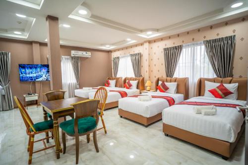 a hotel room with four beds and a table and a television at Siri Nakornpink Chiang Mai Hotel SHA Plus in Chiang Mai