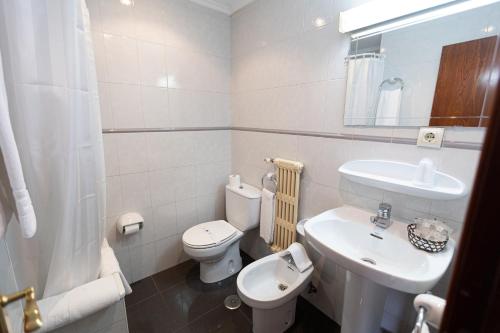 a white bathroom with a sink and a toilet at Hotel Eladia in Cangas de Onís