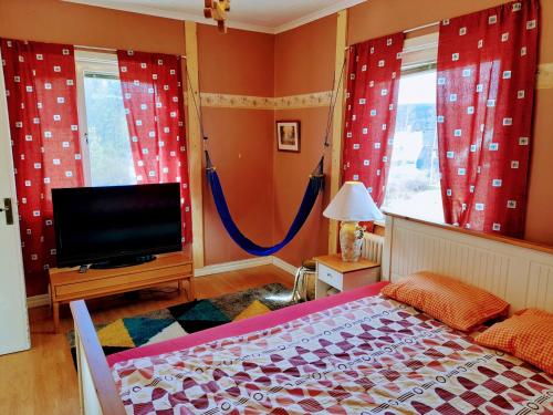 a bedroom with red curtains and a tv and a bed at Bedroom private, 120 from Sandbach in Bräcke