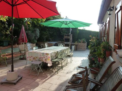 a table and chairs with a red and green umbrella at Gîte Les Iris in Crecy la Chapelle
