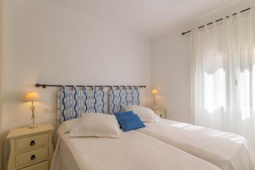een slaapkamer met een wit bed met een blauw hoofdeinde bij Del mar 37 in Colonia de Sant Pere