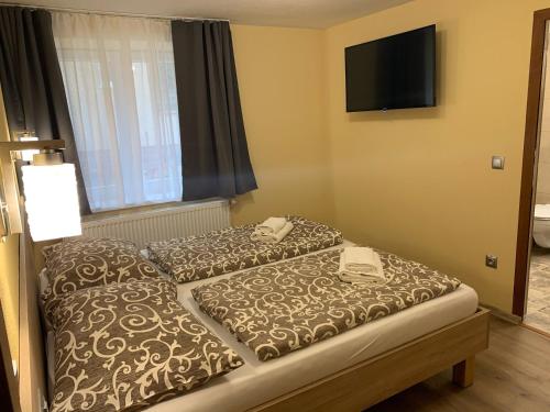 two beds in a hotel room with a television on the wall at Apartmány Hujer 2 in Bojnice