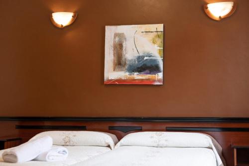 two beds in a room with a painting on the wall at Hotel Eladia in Cangas de Onís