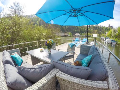 a patio with chairs and a table with a blue umbrella at Hausboot Schleuseninsel in Lahnstein