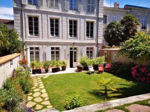 uma grande casa branca com um quintal com plantas em La Résidence des Indes em La Rochelle