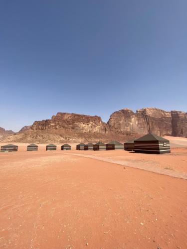 a group of buildings in the desert with mountains in the background at Wadi Rum POLARIS camp in Wadi Rum