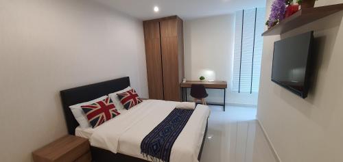 a bedroom with a bed and a flat screen tv at KOZI Square New SGH Cozy Home 7C in Kuching