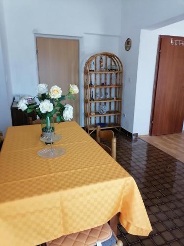 a yellow table with a vase of flowers on it at Apartments Vedrana in Ražanj