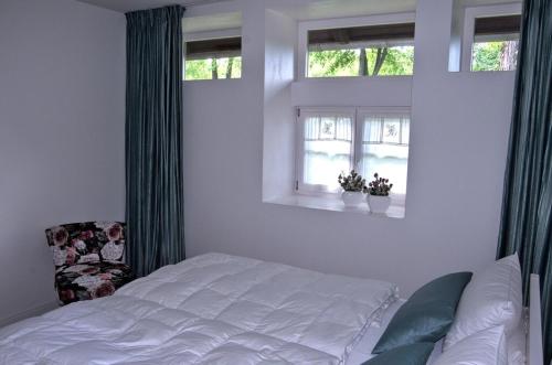 a bedroom with a white bed and two windows at Apartment in ruhiger Wohnlage Sie sind in 3 Minuten am Trebbower See oder in 30 Minuten an der Ostsee in Klein Trebbow