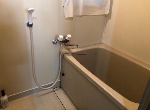 a bath tub in a bathroom with a hose at アルピエa敷地内無料駐車場付き in Kumamoto