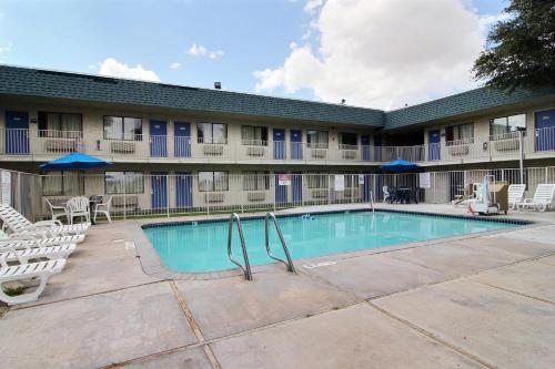 a swimming pool in front of a building with chairs at Motel 6-Fort Stockton, TX in Fort Stockton