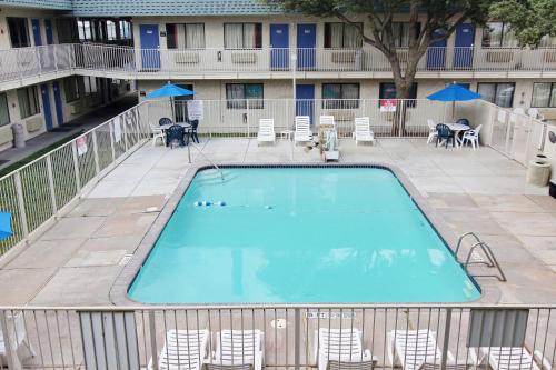 a swimming pool at a hotel with chairs and umbrellas at Motel 6-Fort Stockton, TX in Fort Stockton