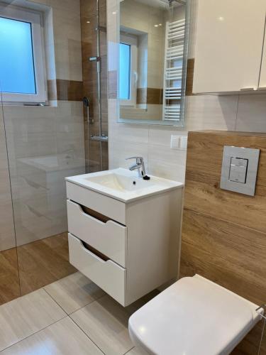 a bathroom with a white sink and a toilet at Pokoje Gościnne U RYBAKA in Karwia