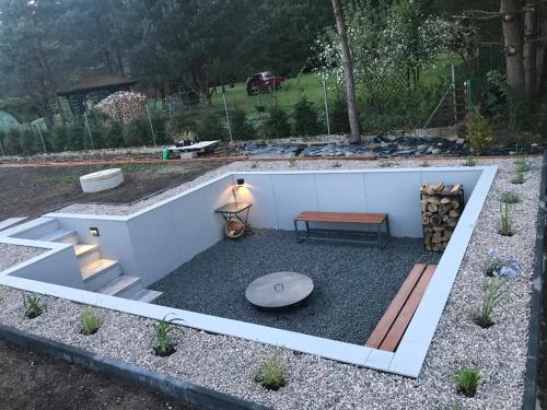 a garden with a bench and a fire pit at Szumiące Trawy - Bory Tucholskie in Tleń