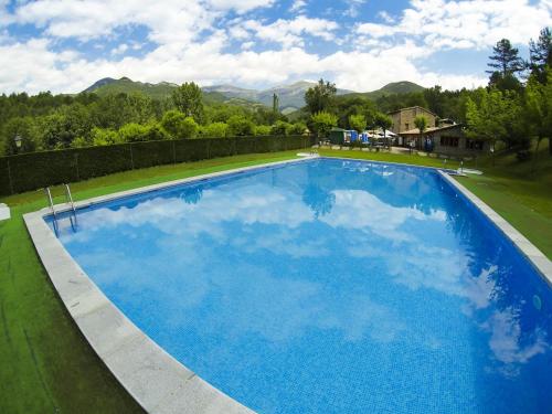 a large blue swimming pool in a yard at Camping L'Espelt in La Pobla de Lillet