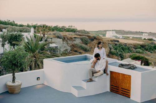a woman standing on the roof of a house with a man sitting on the stairs at Traditional Cave Villas with Jacuzzi, Terrace and Sea view - Sando in Vourvoulos