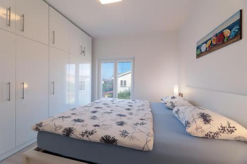 a white bedroom with a bed and a window at Apartment Alan 3 in Vrsi