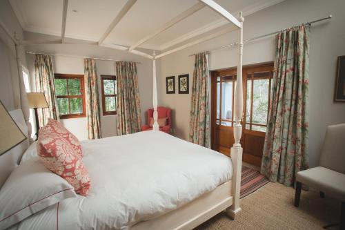 a bedroom with a white bed and two windows at Lombard Villa in Plettenberg Bay