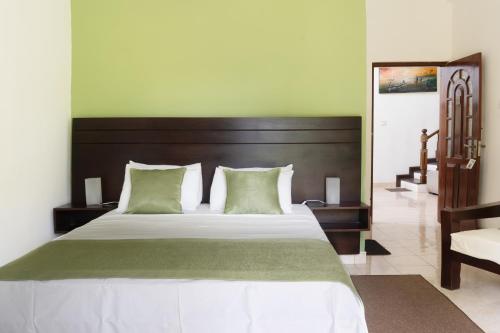 a bedroom with a large bed with green walls at Villa Sarakkuwa in Pamunugama