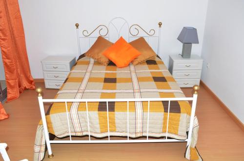 ein Schlafzimmer mit einem Bett mit orangefarbenen und gelben Kissen in der Unterkunft Apartamento Ireny in Praia