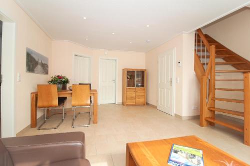 a living room with a table and a staircase at Ferienwohnung Kleekamp Norddeich in Norden