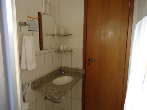a bathroom with a sink and a mirror at Bravo City Rondonópolis in Rondonópolis