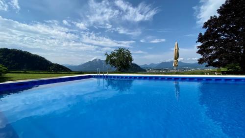 uma grande piscina azul com montanhas ao fundo em Hotel Schöne Aussicht em Salzburgo