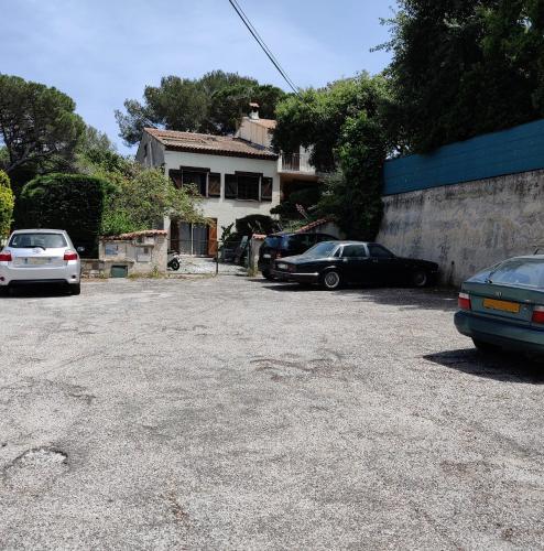 un estacionamiento con autos estacionados frente a una casa en Chambre dans propriété La Croix du Sud, en Le Pradet