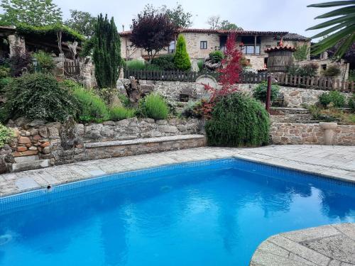 una piscina blu in un cortile con un muro di pietra di As Alburiñas a Bolmente