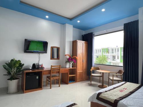 1 dormitorio con escritorio y TV en la pared en ĐỨC THẠNH HOTEL, en Rạch Giá
