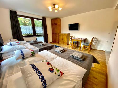 a hotel room with two beds and a living room at Willa FOLK Pieniny in Szczawnica