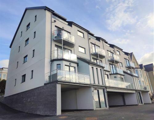 a large white building with balconies on the side of it at Modern apartment with breathtaking sea views in Penmaen-mawr