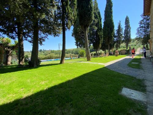 un parque con césped verde, árboles y acera en Il Castagnolo B&B, en San Gimignano