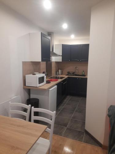 a kitchen with a microwave and a table with chairs at Appartement de l'épée in Dieppe